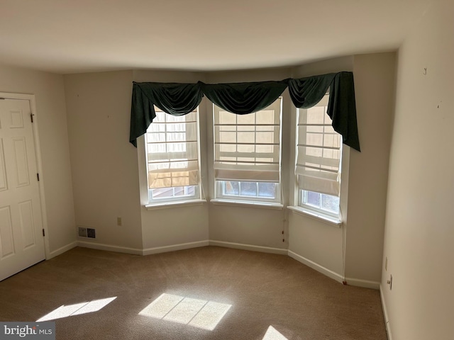 carpeted empty room featuring visible vents and baseboards