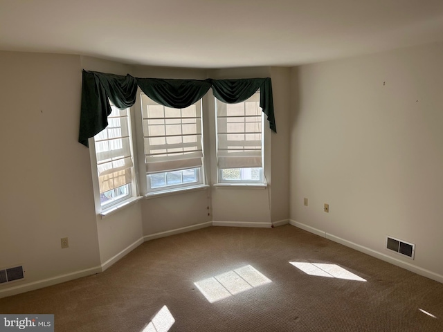 spare room featuring carpet flooring, baseboards, and visible vents