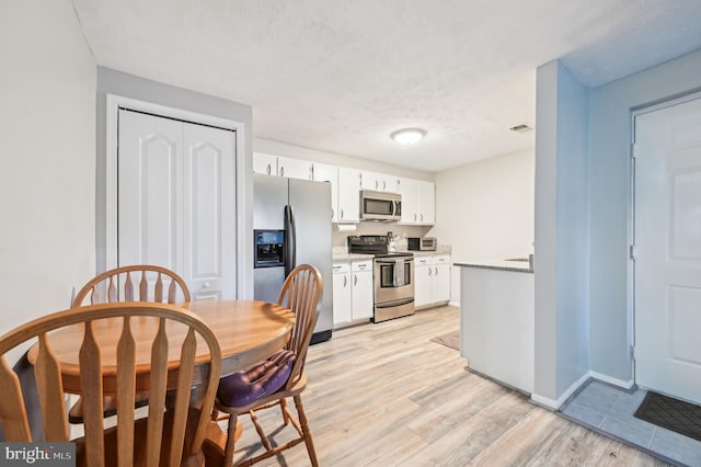 kitchen featuring white cabinetry, light wood-style flooring, visible vents, and appliances with stainless steel finishes