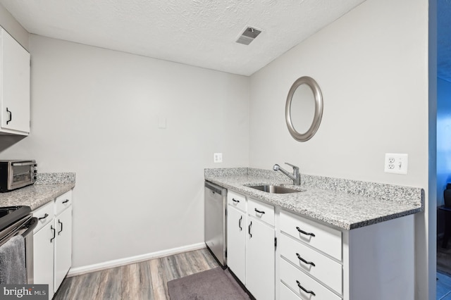 kitchen with wood finished floors, electric range oven, a sink, a textured ceiling, and stainless steel dishwasher