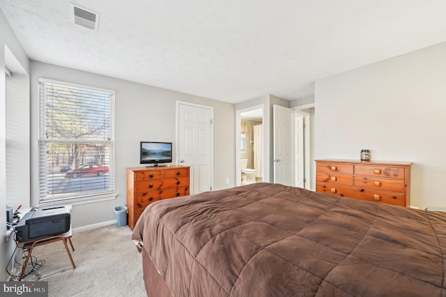 bedroom featuring baseboards, visible vents, ensuite bath, a textured ceiling, and light carpet