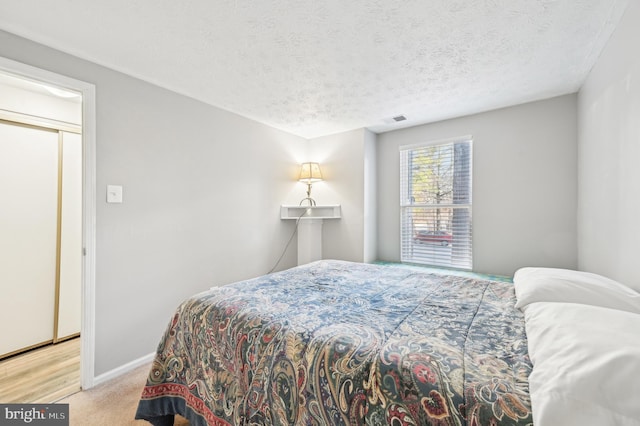 carpeted bedroom with visible vents, baseboards, and a textured ceiling