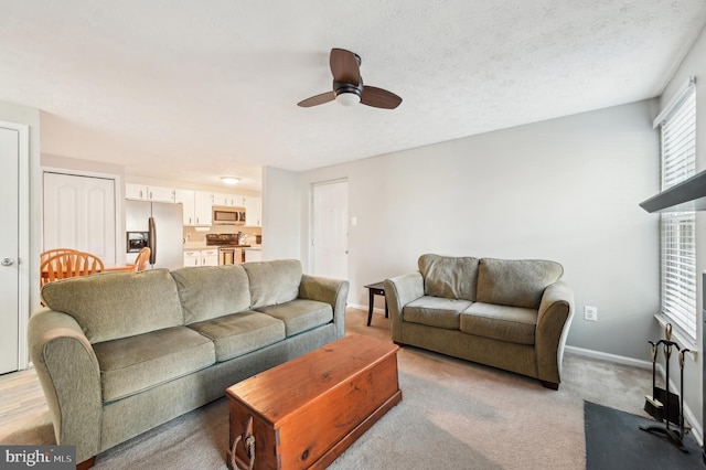 living room featuring baseboards, a textured ceiling, ceiling fan, and a fireplace