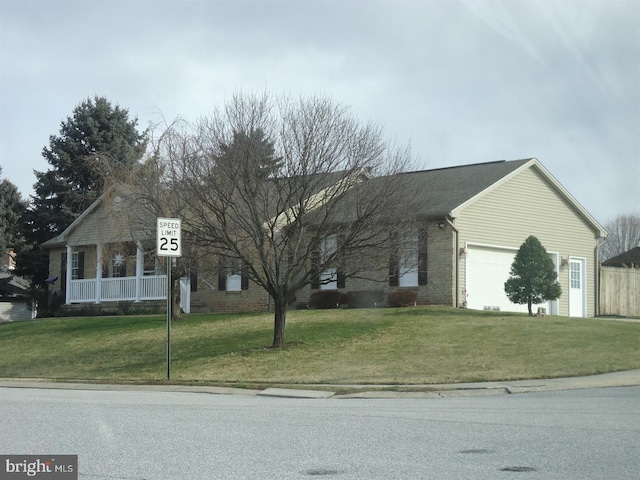 view of front of home with a front yard, a garage, and brick siding