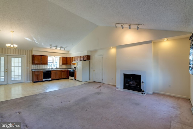 unfurnished living room with light carpet, a fireplace, rail lighting, french doors, and a textured ceiling