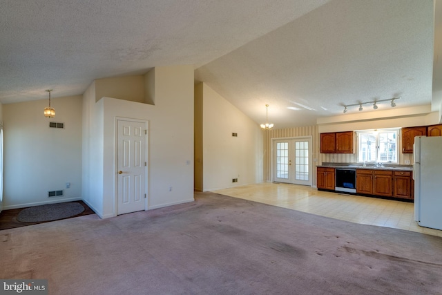 kitchen with visible vents, light carpet, brown cabinets, freestanding refrigerator, and dishwasher