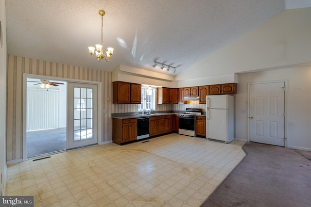 kitchen with a sink, range with gas stovetop, freestanding refrigerator, wallpapered walls, and dishwasher