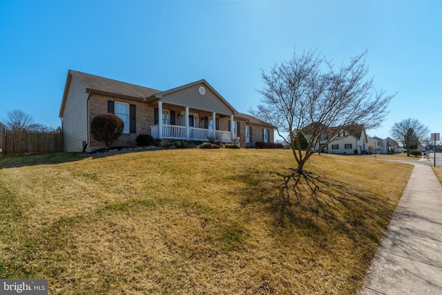 view of front facade with brick siding, a porch, a front lawn, and fence