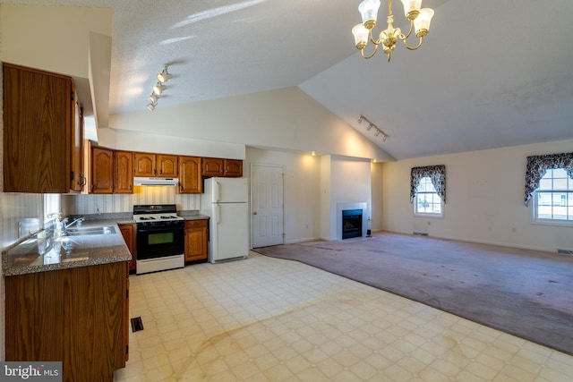 kitchen featuring dark countertops, brown cabinets, range, freestanding refrigerator, and a sink