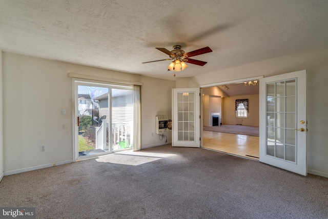 carpeted spare room with a ceiling fan, heating unit, a textured ceiling, french doors, and baseboards