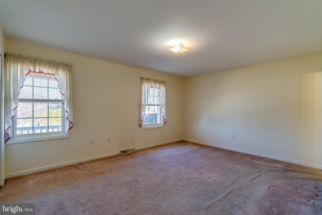 empty room featuring carpet flooring, plenty of natural light, and visible vents