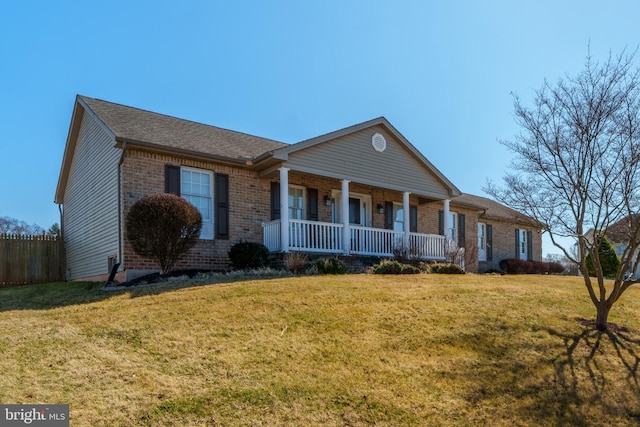 view of front of property featuring a front lawn, fence, roof with shingles, covered porch, and brick siding