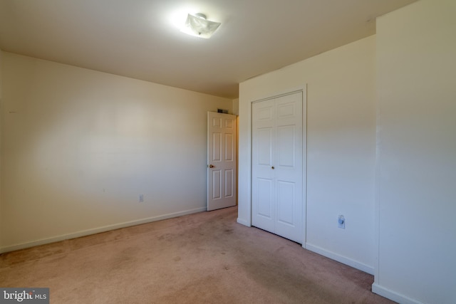 unfurnished bedroom featuring a closet, baseboards, and carpet floors