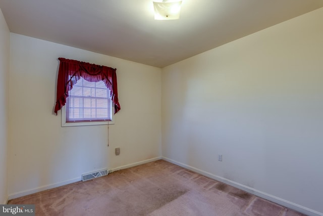 carpeted spare room featuring baseboards and visible vents