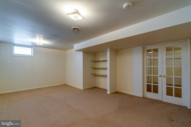 below grade area with french doors, visible vents, carpet floors, and baseboards