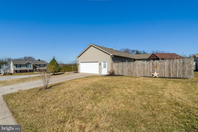 view of side of home featuring concrete driveway, an attached garage, fence, and a lawn