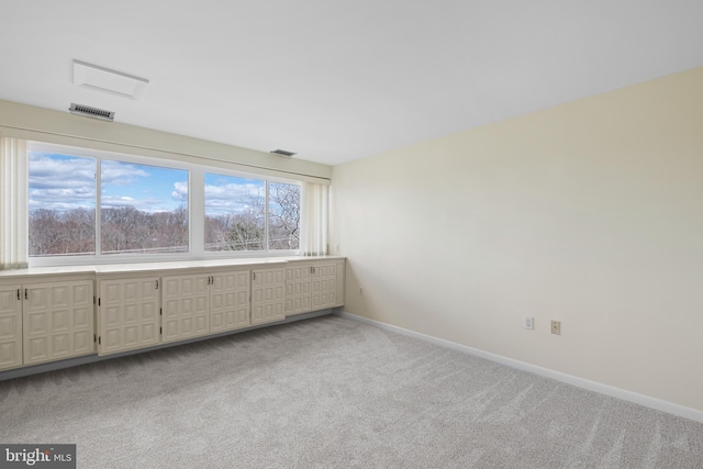 spare room with light carpet, visible vents, and baseboards