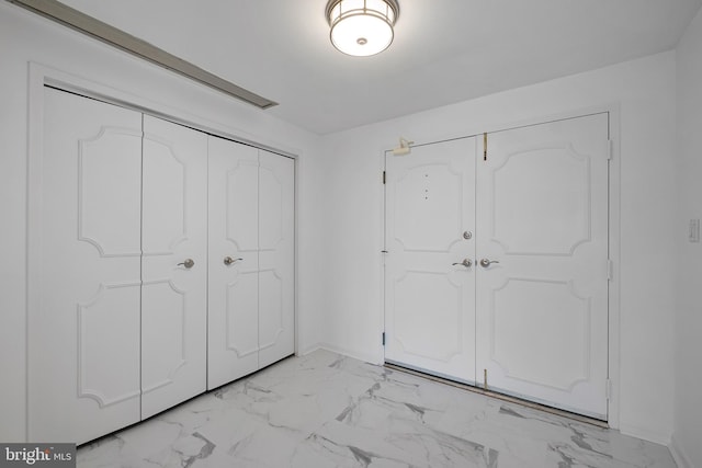 unfurnished bedroom with marble finish floor and baseboards