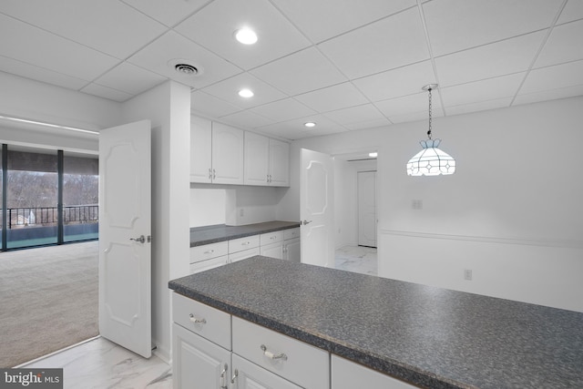 kitchen with visible vents, white cabinets, a drop ceiling, dark countertops, and marble finish floor