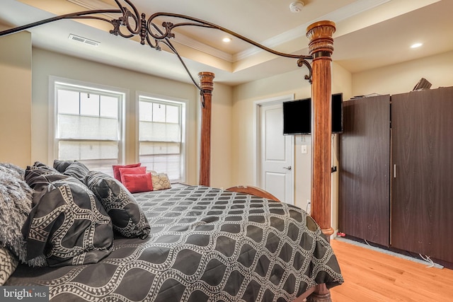 bedroom with recessed lighting, a raised ceiling, visible vents, light wood-style floors, and ornamental molding