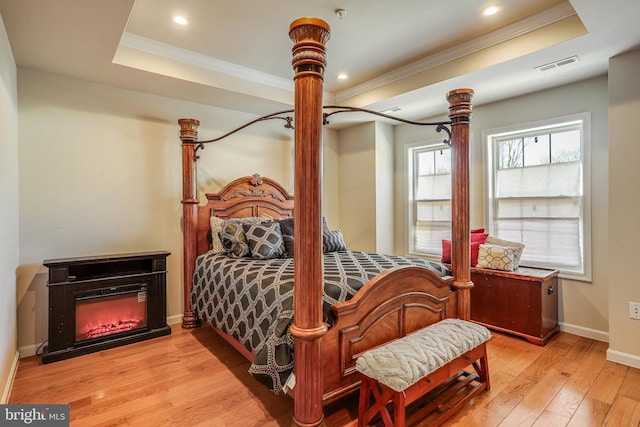 bedroom featuring visible vents, ornamental molding, a raised ceiling, and hardwood / wood-style floors