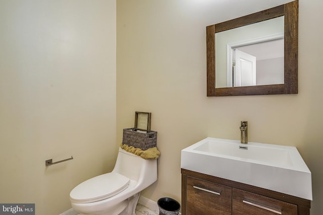 half bath featuring vanity, toilet, and baseboards