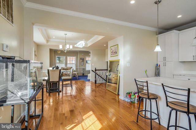 kitchen featuring light wood-type flooring, a notable chandelier, white cabinets, and crown molding