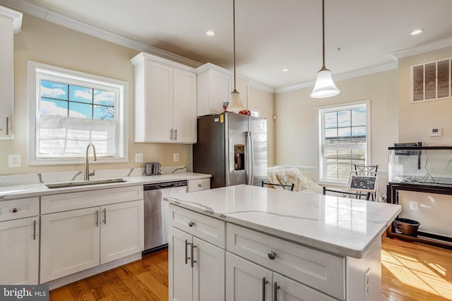 kitchen featuring a sink, white cabinetry, appliances with stainless steel finishes, light wood finished floors, and crown molding