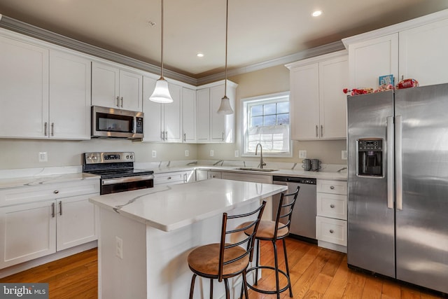 kitchen with stainless steel appliances, light wood-type flooring, white cabinets, and a sink