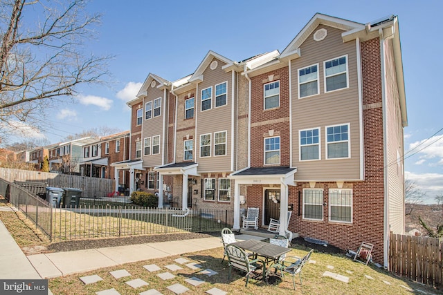 view of property featuring brick siding, a fenced front yard, and a residential view