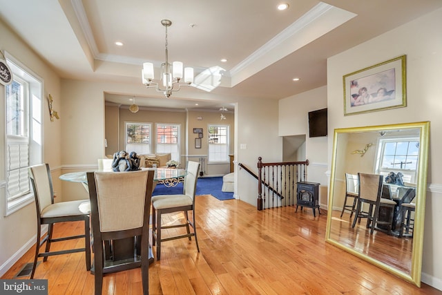 dining area with a wealth of natural light, a raised ceiling, and light wood-style flooring