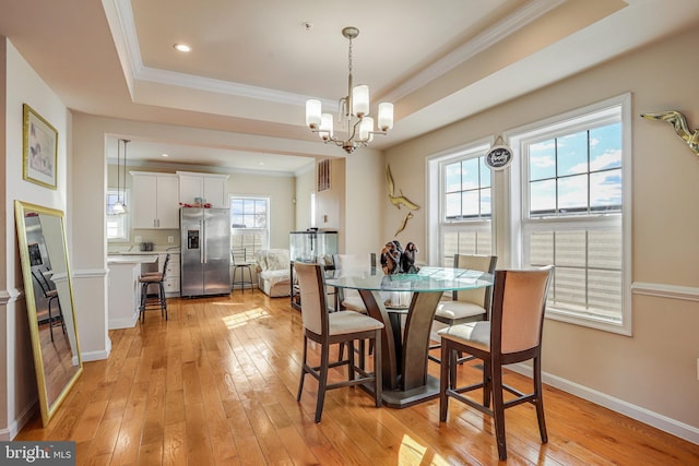 dining area with light wood-style floors, baseboards, ornamental molding, and a raised ceiling