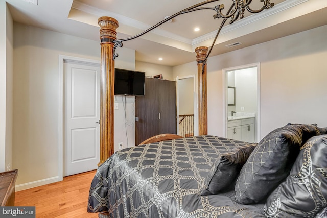 bedroom featuring baseboards, visible vents, a raised ceiling, crown molding, and light wood-style floors