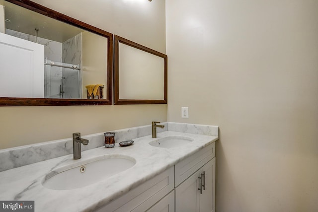 full bath with double vanity, a marble finish shower, and a sink