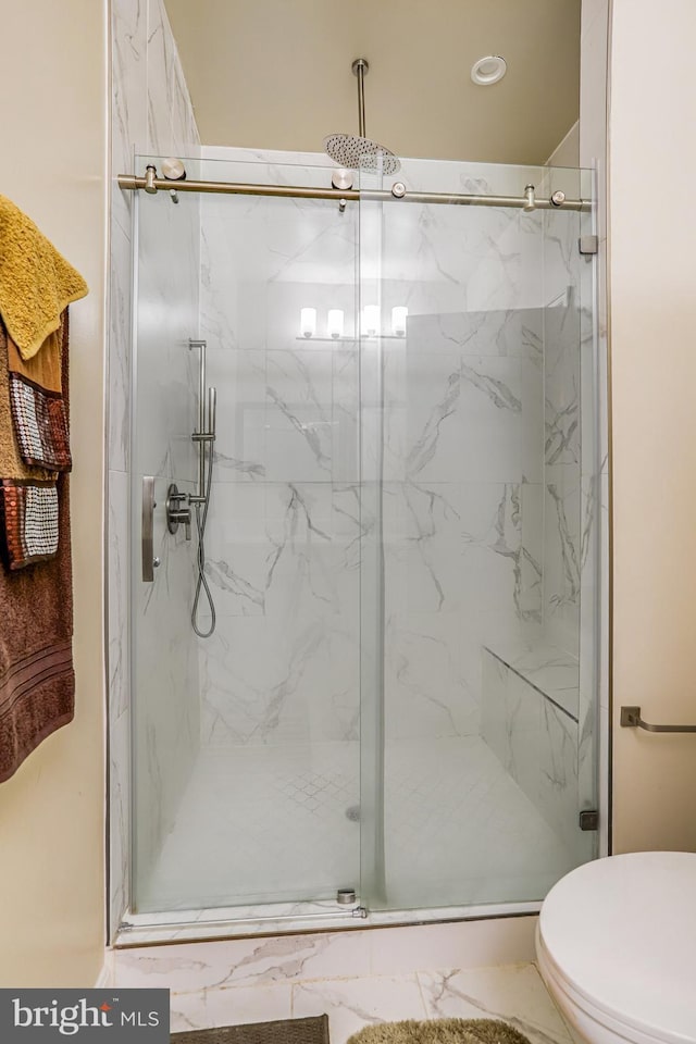 bathroom featuring toilet and a marble finish shower