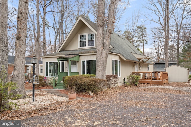 view of front of property featuring roof with shingles, an outdoor structure, and a deck