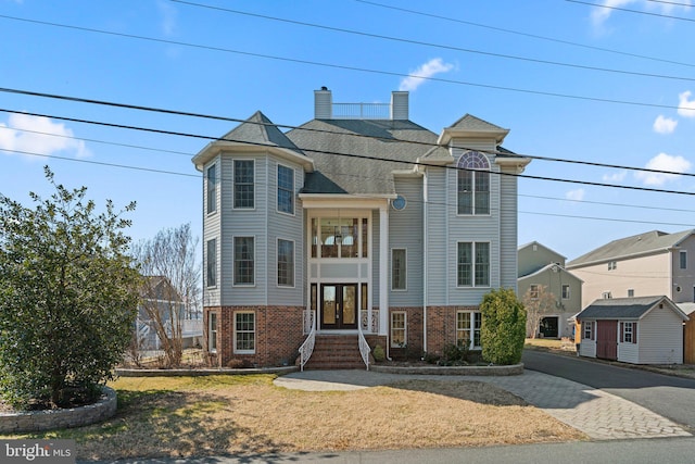 view of front of property featuring french doors, a chimney, and brick siding