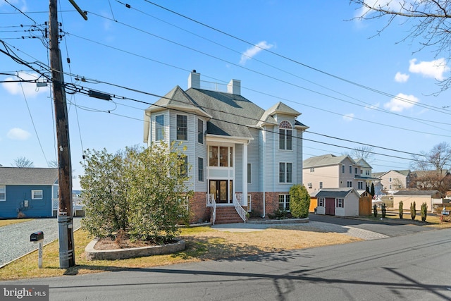 view of front of property featuring a chimney, a residential view, and brick siding