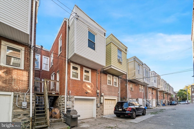 exterior space featuring stairway, cooling unit, a residential view, a garage, and brick siding