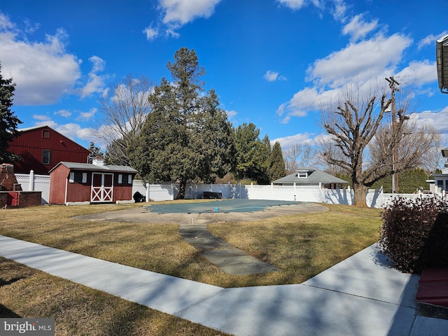 view of yard with a storage unit, a fenced in pool, an outdoor structure, and a fenced backyard