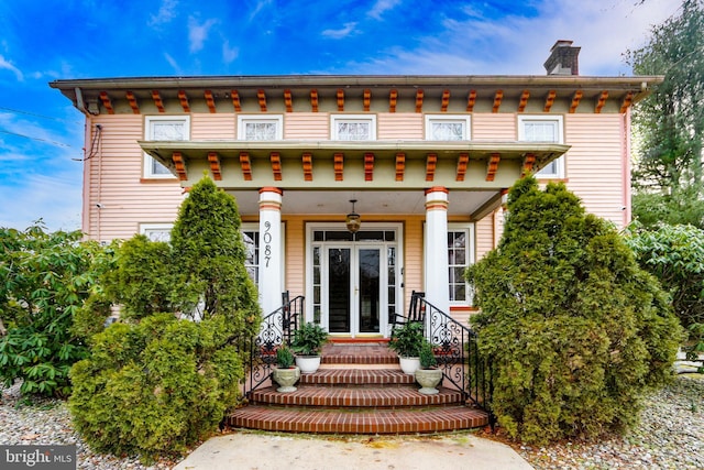 italianate-style house featuring a chimney and french doors