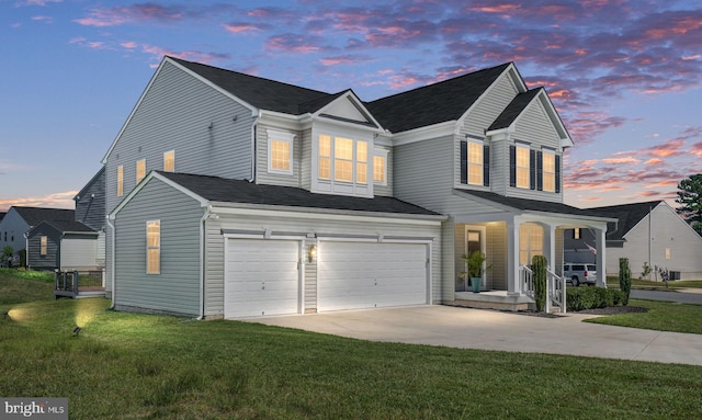 traditional-style home with concrete driveway, covered porch, a yard, and an attached garage