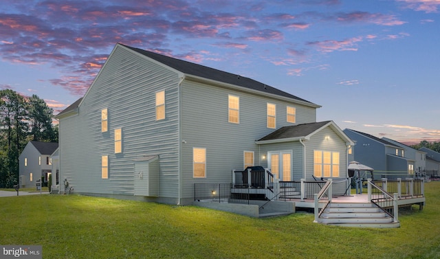 back of property at dusk featuring a yard and a wooden deck