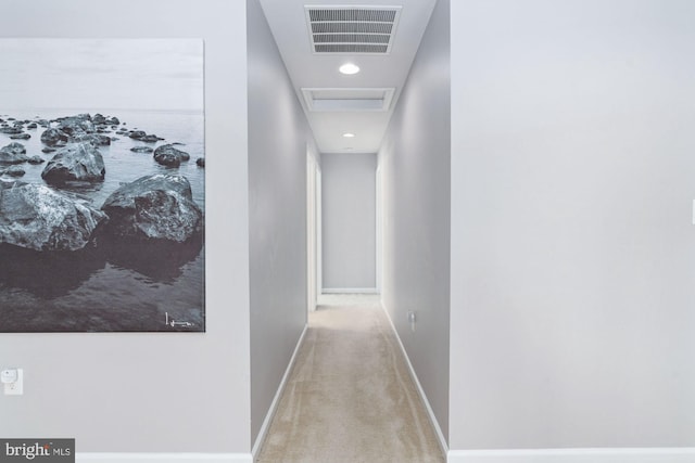 hall featuring baseboards, carpet flooring, visible vents, and attic access
