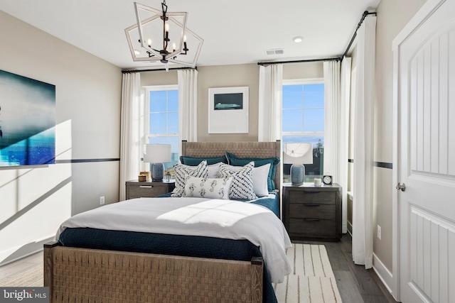 bedroom featuring wood finished floors, visible vents, and an inviting chandelier