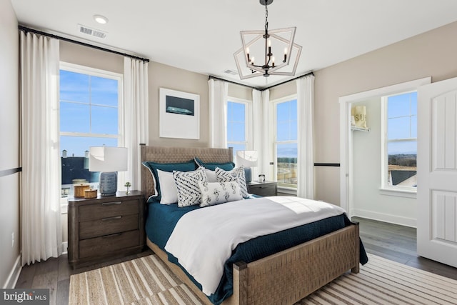 bedroom featuring baseboards, a notable chandelier, visible vents, and hardwood / wood-style floors