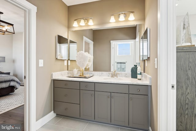 ensuite bathroom with baseboards, tile patterned flooring, vanity, and connected bathroom