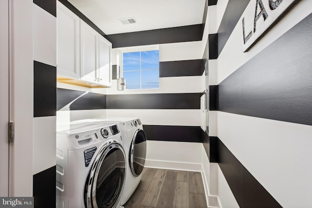 clothes washing area with washer and dryer, visible vents, and wood finished floors