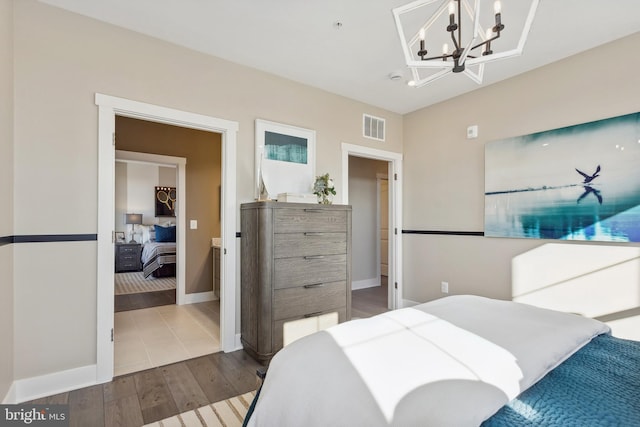 bedroom with baseboards, visible vents, a chandelier, and wood finished floors