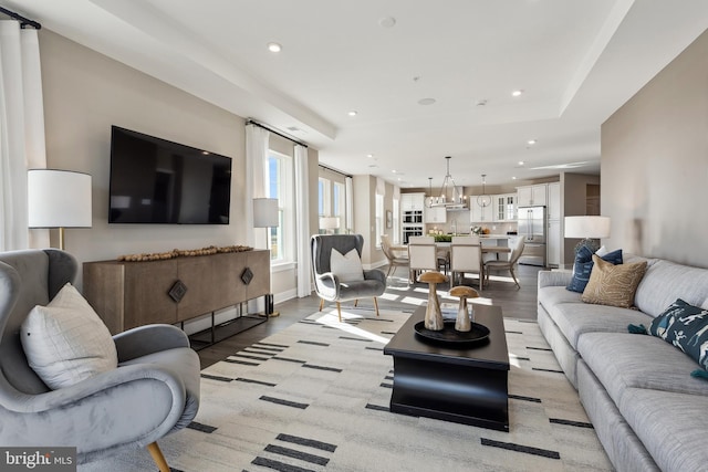 living room featuring a chandelier, light wood-type flooring, baseboards, and recessed lighting